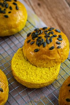 pumpkin spiced buns cooling on a rack, with seeds sprinkled on top