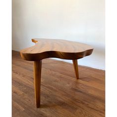 a wooden table sitting on top of a hard wood floor next to a white wall