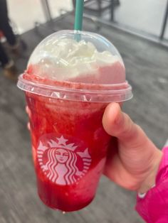 a person holding up a drink with whipped cream and toppings in it's cup