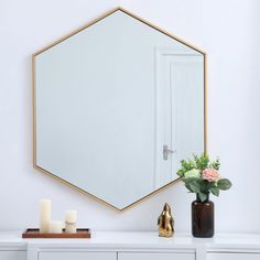 a white dresser topped with a mirror next to a vase filled with flowers and candles