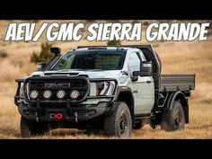 the front end of a white truck in a field with words above it that says aev / gmc sierra grande