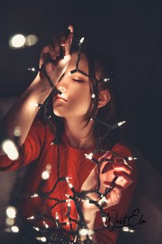 a woman with her eyes closed is surrounded by christmas lights