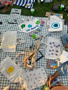 several children's t - shirts and other items on a picnic table in the grass