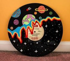 a record with an image of the planets and stars on it, sitting in front of a yellow wall