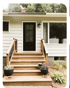 the front steps and side porch of a white house with black door, planters on either side