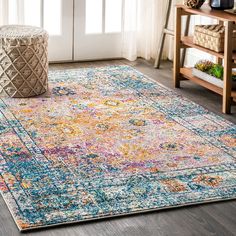 a colorful area rug with an ornate design on the center and bottom, in front of a window