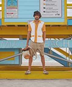 a man standing in front of a blue and yellow lifeguard tower with his hand on the handle