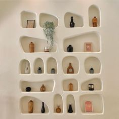 several shelves with vases and other items on them in a white walled wall area