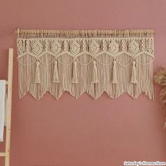 there is a wall hanging with tassels in the corner next to a ladder