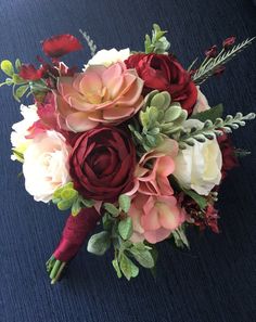 a bridal bouquet with red, white and pink flowers on a dark blue background