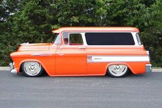 an orange and white truck parked in front of some trees