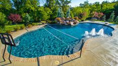 an outdoor swimming pool surrounded by landscaping and trees