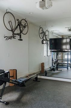 there is a bike and exercise equipment in the room with mirrors on the wall behind it