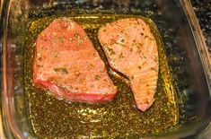 two raw salmon fillets in a pan with seasoning on the side and green pepper sprinkled on top