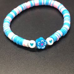 a blue and white beaded bracelet with a flower in the center on a black surface