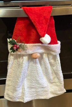 a white towel with a red santa hat hanging from it's side in front of an oven