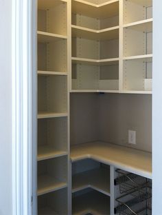 an empty closet with white shelves and wire baskets