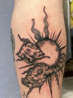 a black and white tattoo on the leg of a person with a sun in the background