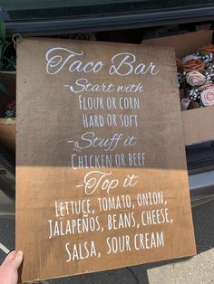 a person holding up a sign that reads taco bar start with flour or corn, hard or soft stuff, chicken or beef