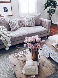 a living room filled with furniture and flowers on top of a coffee table in front of a window