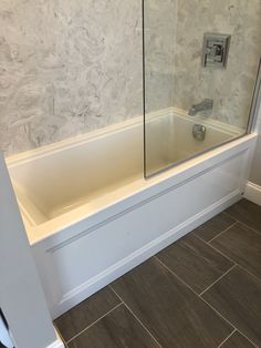 a bathroom with a glass shower door next to a bathtub and tile flooring