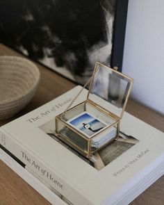 a stack of books sitting on top of a wooden table next to a bowl and vase