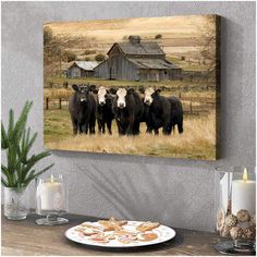 a group of cows in a field with a barn in the background canvas wall art print