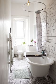 a white bath tub sitting in a bathroom next to a toilet and shower head mounted on a wall