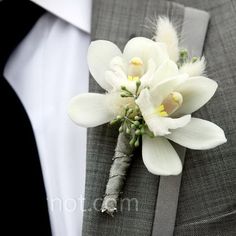 a boutonniere with white flowers and feathers on the lapel of a man