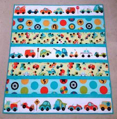 a quilted placemat with cars and trucks on it, sitting on the floor