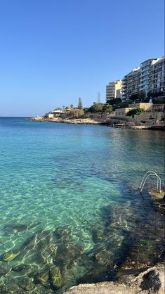 clear blue water with buildings in the background on a sunny day at an ocean shore