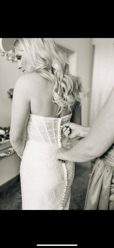 a woman in a wedding dress getting ready