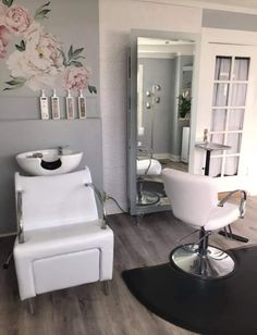 a salon with white chairs and flowers on the wall