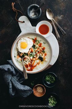 an overhead view of a bowl of food with eggs and sauces on the side