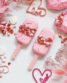 pink ice cream pops are arranged on a white surface with hearts and flowers around them