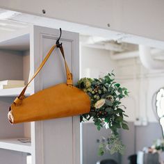 a yellow purse hanging from the side of a white door with a flower arrangement on it