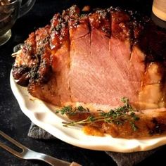 a large piece of meat sitting on top of a white plate next to silverware