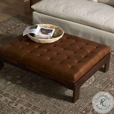 a brown leather ottoman sitting on top of a rug