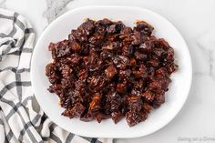 raisins in a white bowl on top of a black and white checkered towel