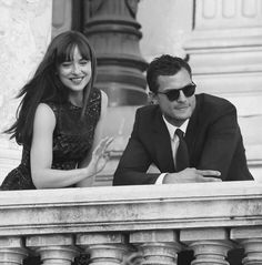 a man and woman sitting next to each other in front of a building with columns