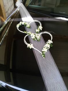 the wedding car is decorated with flowers and ribbons in the shape of two heart - shaped hearts