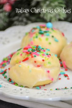 three cookies on a plate with sprinkles and christmas decorations in the background