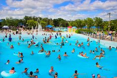 a large pool filled with people swimming and playing in the water while surrounded by trees