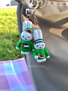 two key chains attached to a purse with bunny ears on it's back pocket