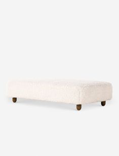 a white bench with wooden legs and a sheepskin seat cover on top of it