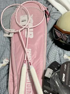 two tennis racquets and a helmet are laying on the bed next to each other