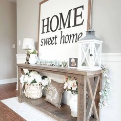 a wooden table topped with white flowers next to a sign that says home sweet home