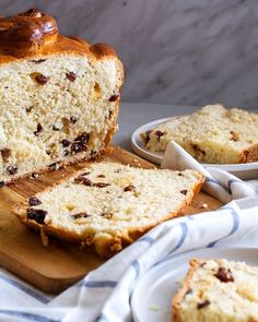 a loaf of bread sitting on top of a wooden cutting board next to slices of cake