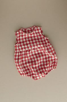 Product photos - red gingham. The model is wearing a romper in yellow gingham color. All-day comfort is guaranteed with this sleeveless romper crafted from gingham linen. The fabric is soft, breathable, and light on the skin. For simple changing, the romper is designed with popper snap fastenings on the shoulders and bottom. The waist seam in the middle adds a nice final touch to an adorable silhouette, and elasticated leg cuffs secure the romper in place. This baby romper is designed to be comfortably loose-fitting and allow for growth as the baby grows. Sleeveless Jumpsuits And Rompers For Spring Picnic, Sleeveless Summer Jumpsuits And Rompers For Picnic, Plaid Cotton Bubble Romper For Summer, Summer Cotton Plaid Bubble Romper, Summer Plaid Cotton Bubble Romper, Playful Gingham Cotton Bubble Romper, Playful Red Jumpsuits And Rompers For Summer, Spring Gingham Jumpsuits And Rompers, Sleeveless Gingham Jumpsuits And Rompers For Summer