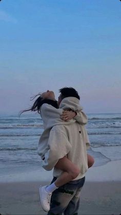 two people are hugging on the beach